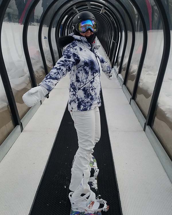 Mandy on snowboard riding snowboard lift back to top of mountain